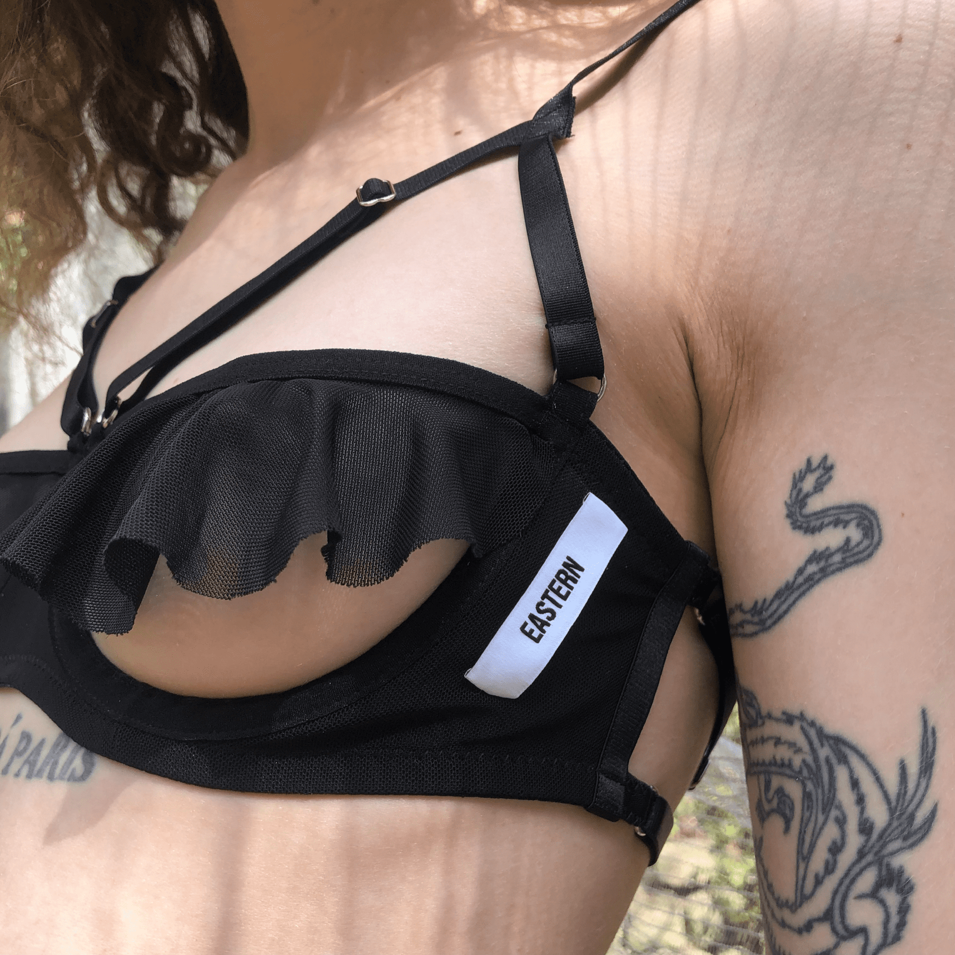 Product image featuring a black mesh lingerie bra with an Eastern logo. This alluring bra showcases a combination of sheer mesh fabric and intricate Eastern-themed branding, offering a blend of sensuality and style in intimate apparel.